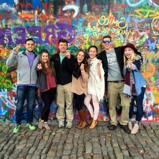 布拉格一条鹅卵石街道上，七名在国外学习的TCU学生站在一面明亮的喷漆涂鸦墙前.